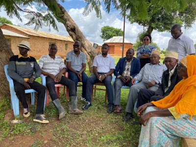 A group of Isanzu elders sit in a circle outside. 