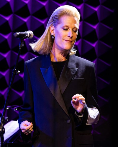A blond woman at a microphone, snapping her fingers.