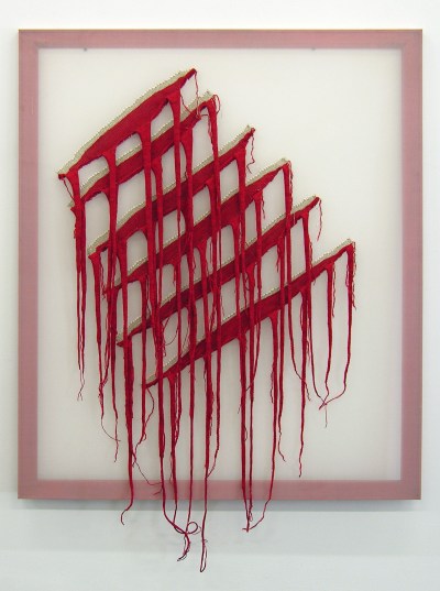 A woven work that features a white background with gashes in it. The gashes reveal spills of red yarn.
