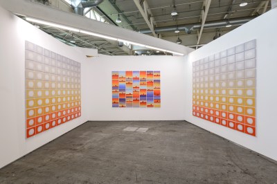 A white-walled room with orange paintings on the wall.