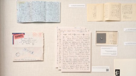A vitrine with handwritten texts, envelopes, and pictures of men.