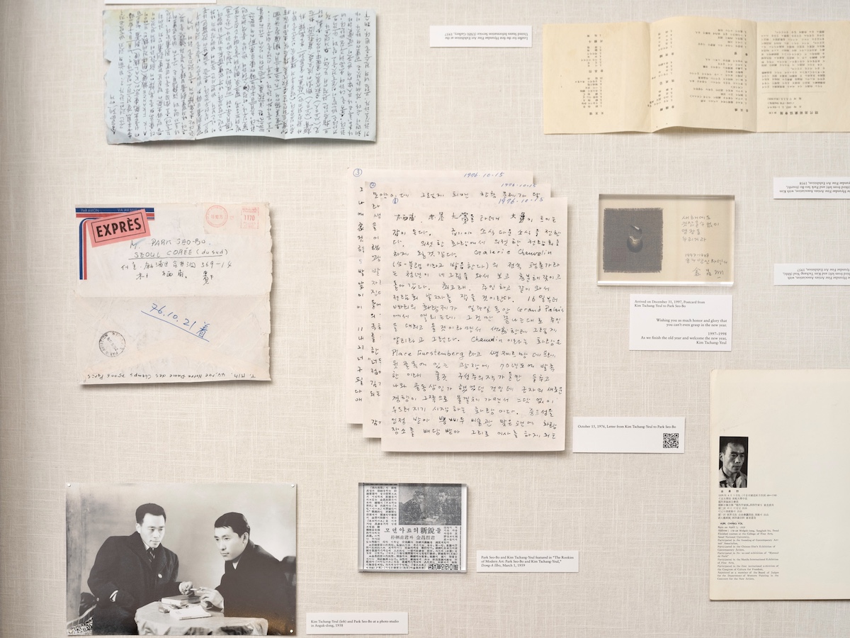 A vitrine with handwritten texts, envelopes, and pictures of men.