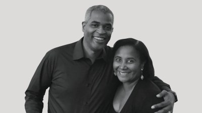 A silhouetted black-and-white portrait of a Black man and a Black woman on a gray background.