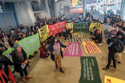 A large group of people with big signs in a crowded lobby.