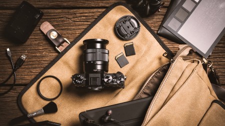 photography gear on wooden table, digital camera lens and other accessories.