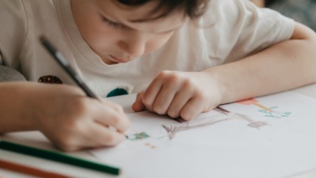 A little boy drawing with colored pencils.