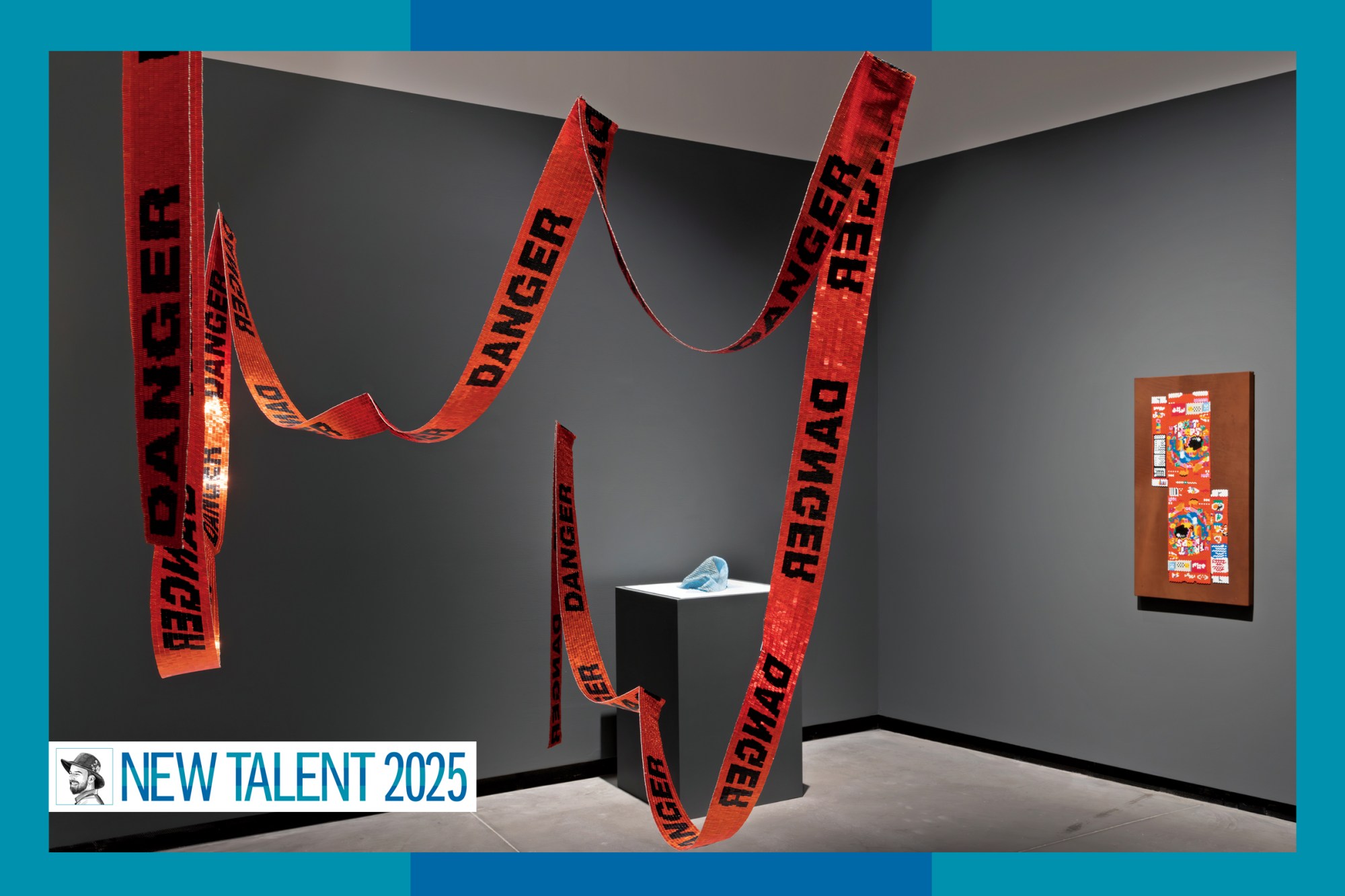 A grey-walled gallery with orange beaded orange "Danger" tape hanging from teh ceiling.