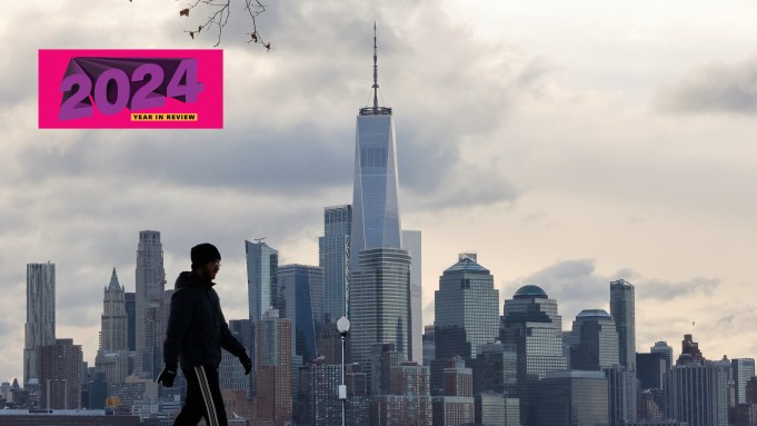 A man walks on snow in front of the New York skyline.
