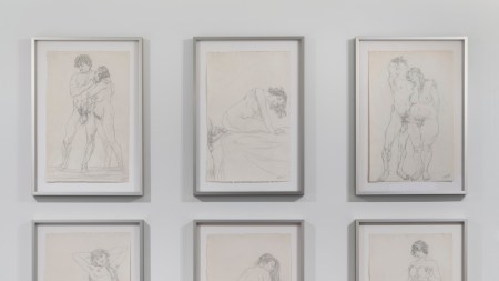 Nine pencil drawings are framed and hung on a wall. Most depict couples or single figures, all nude.