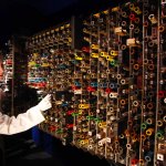 A woman in a white jacket touches one of many coils on a machine resembling a large grid.
