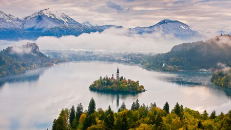 An island on a lake with mountains in the background.