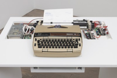 A vintage typewriter with circuitry behind