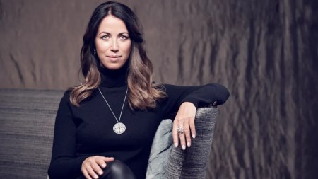 A woman in a black turtleneck looks at the camera.