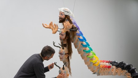 A white man is arranging a stack of sculpted heads.