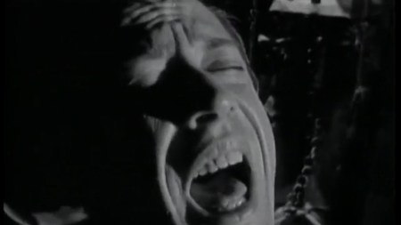 A black and white up close photo of a white man screaming in agony or orgasm.
