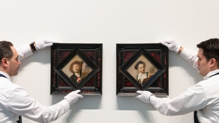 Two guys holding two amazing paintings.