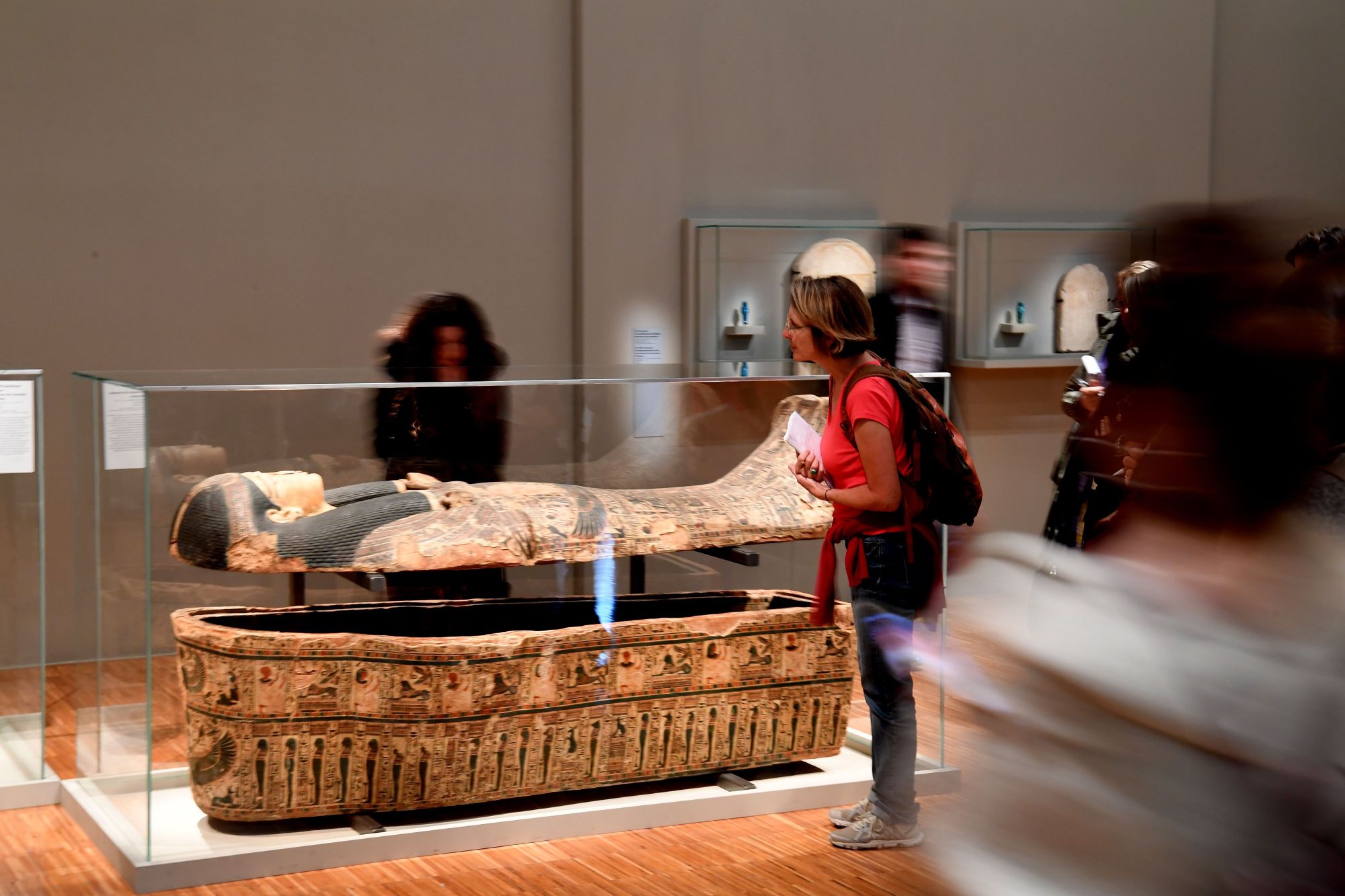 People look at an ancient Egyptian sarcophagus part of the 'Serve the Gods of Egypt' exhibition showing at the Museum of Grenoble, southern eastern France On October 23, 2018. - Based on the Grenoble collections and supplemented by 200 works from the Louvre Museum and others loaned by European museums, the exhibition offers an approach to Theban society during the Third Intermediate Period (1069-664 BC), around the temple of Karnak, the main place of worship of the god Amon. (Photo by JEAN-PIERRE CLATOT / AFP)        (Photo credit should read JEAN-PIERRE CLATOT/AFP via Getty Images)