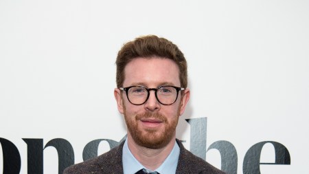 A red-haired man with a beard and glasses smiles for the camera.