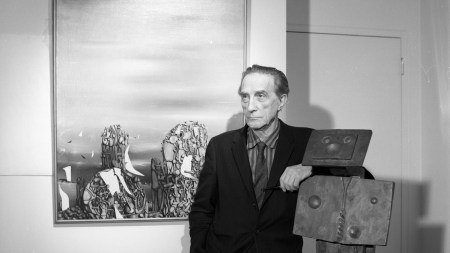 A man with an arm leaned against a sculpture of a man.