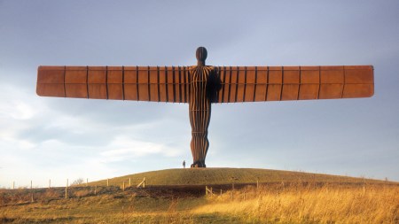 A monumental sculpture of an angel spreading its wings above a field.