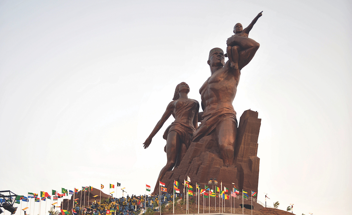 A large monuments of a man, woman, and child pointing up to the sky