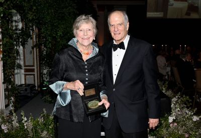 A man in a suit and a woman in a dress holding an award.