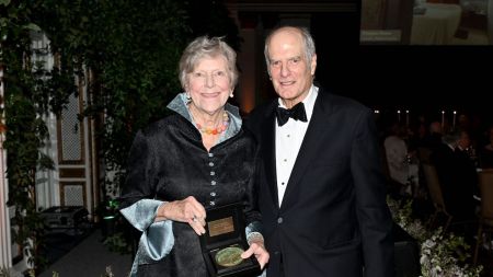 A man in a suit and a woman in a dress holding an award.