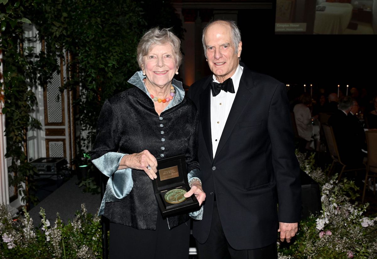 A man in a suit and a woman in a dress holding an award.