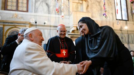 A man in papal robes greeting a woman in a black headscarf.
