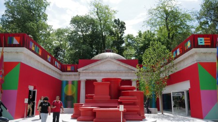 People outside a pavilion that has been covered in red and green monchromes.