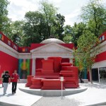 People outside a pavilion that has been covered in red and green monchromes.