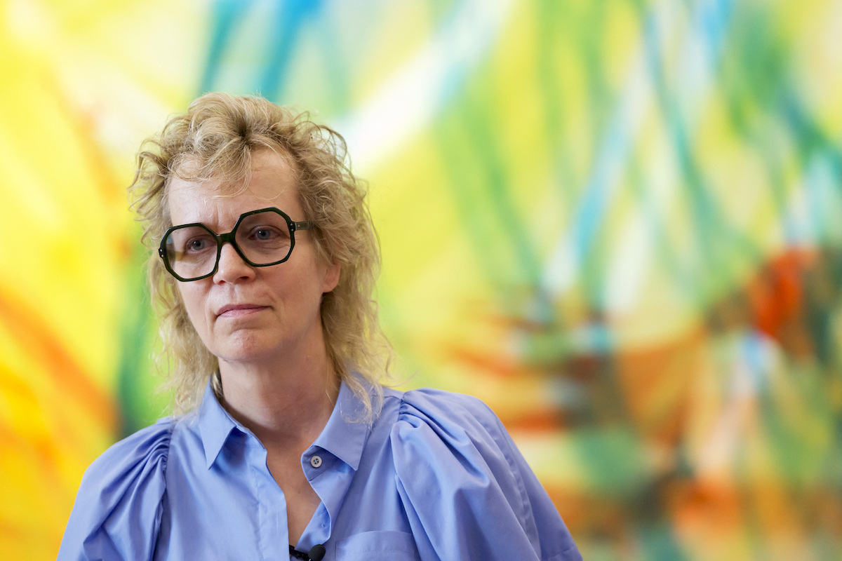 A woman in front of an abstract painting.