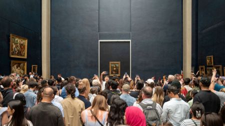 A crowd of people before a painting.