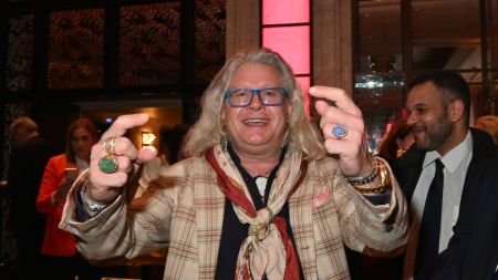 A man with long white hair smiling at the camera.