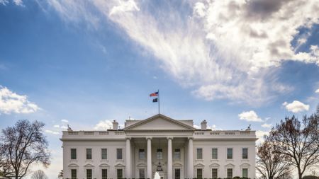 A white columned building with a fountain in front of it.