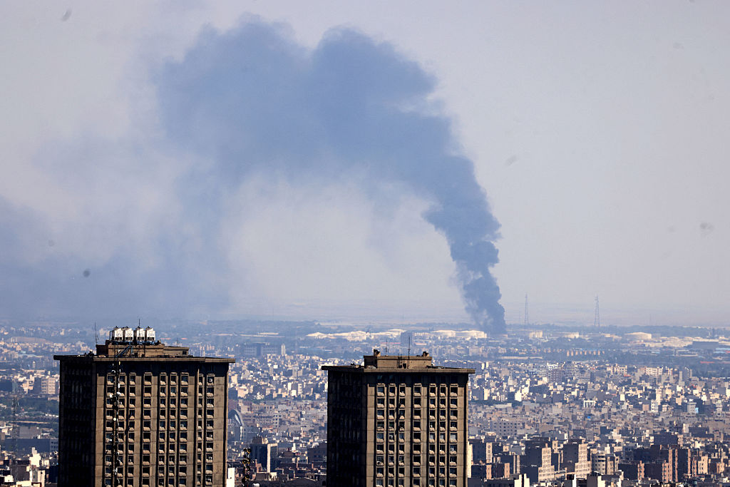 TOPSHOT - Smoke billows in the distance from an oil refinery following an Israeli strike on the Iranian capital Tehran on June 17, 2025. Israel and Iran exchanged fire again, the fifth day of strikes in their most intense confrontation in history, fuelling fears of a drawn-out conflict that could engulf the Middle East. (Photo by ATTA KENARE / AFP) (Photo by ATTA KENARE/AFP via Getty Images)