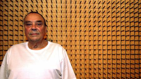 A man in front of nails arranged in a grid.