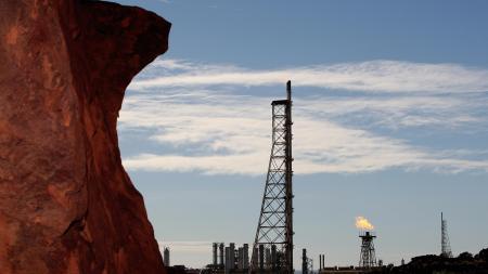 Gas flares (R-at back) at the Woodside operated North West Shelf Venture with rock (L-foreground) are shown on the Burrup Peninsula in the north of Western Australia on June 17, 2008. Piles of red rock which typify the Burrup area are the site for perhaps one million pieces of Aboriginal rock engravings several thousands of years old and considered by some to be the greatest concentration of such ancient art in the world. The peninsula in the resource-rich Pilbara region is also home to increasing amounts of industrial activity, including a gas processing plant, a fertiliser plant and iron ore facilities which are threatening the rock images of long-extinct animals and what are believed to be mythological creatures.  AFP PHOTO / Greg WOOD (Photo credit should read GREG WOOD/AFP via Getty Images)