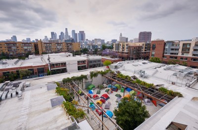 Aerial view of a gallery with a courtyard full of tents. Skyscrapers loom in the background.