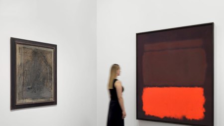 A woman looks at an abstract color field painting by Rothko at right. At left is a muddied painted portrait of a man by Giacometti.