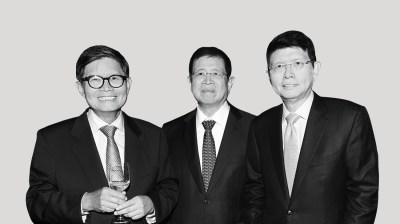 A silhouetted black-and-white portrait of three Asian men all with glasses and all wearing suits and ties on a gray background. The man on the left holds a half-filled wine glass.