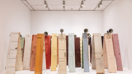 Dozens of doors are sliced in half, their parts leaned against one another to form an A-frame. Megaphones rest on top of several.