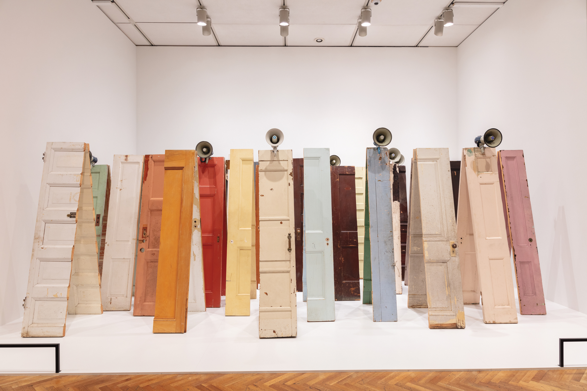 Dozens of doors are sliced in half, their parts leaned against one another to form an A-frame. Megaphones rest on top of several.