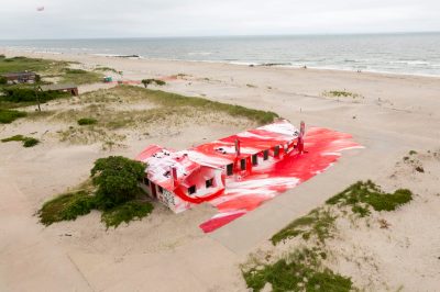 A beachside house covered in red and white paint.