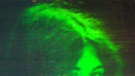A hologram depicts a woman blowing a kiss, a 3D moving image rendered in shades of green
