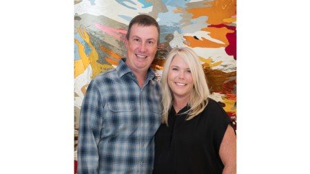 A white man and a white woman in front of an abstract painting.