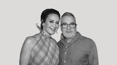 A silhouetted black-and-white portrait of a white woman and white man posing together on a gray background.