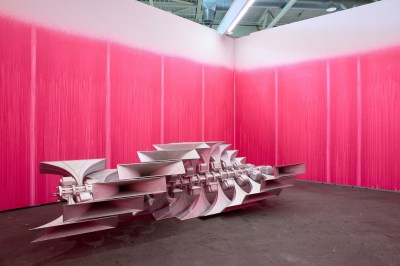 A metalic sculpture surrounded by pink walls.