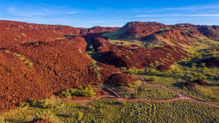 A red mountain range with trees at the foot of its peaks.