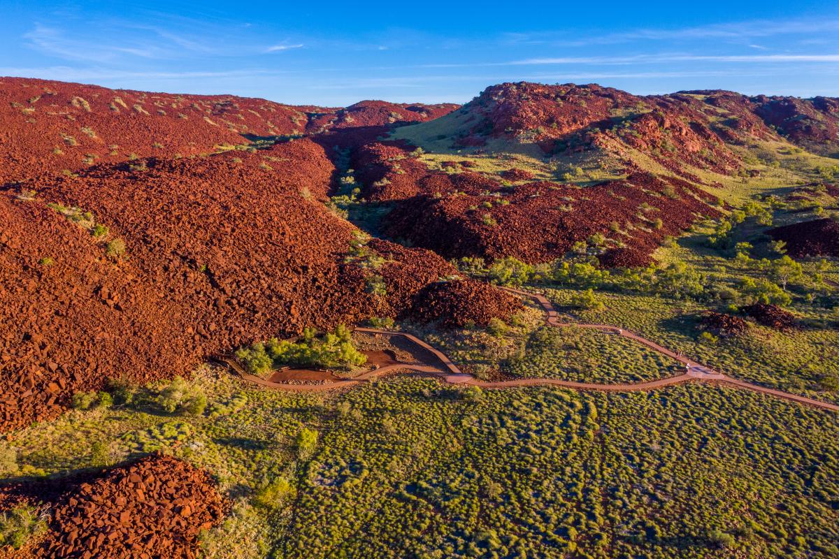 A red mountain range with trees at the foot of its peaks.